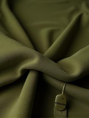 Close-up of a sustainably made hemp tunic in a muted green, with '100% Biodegradable' badge